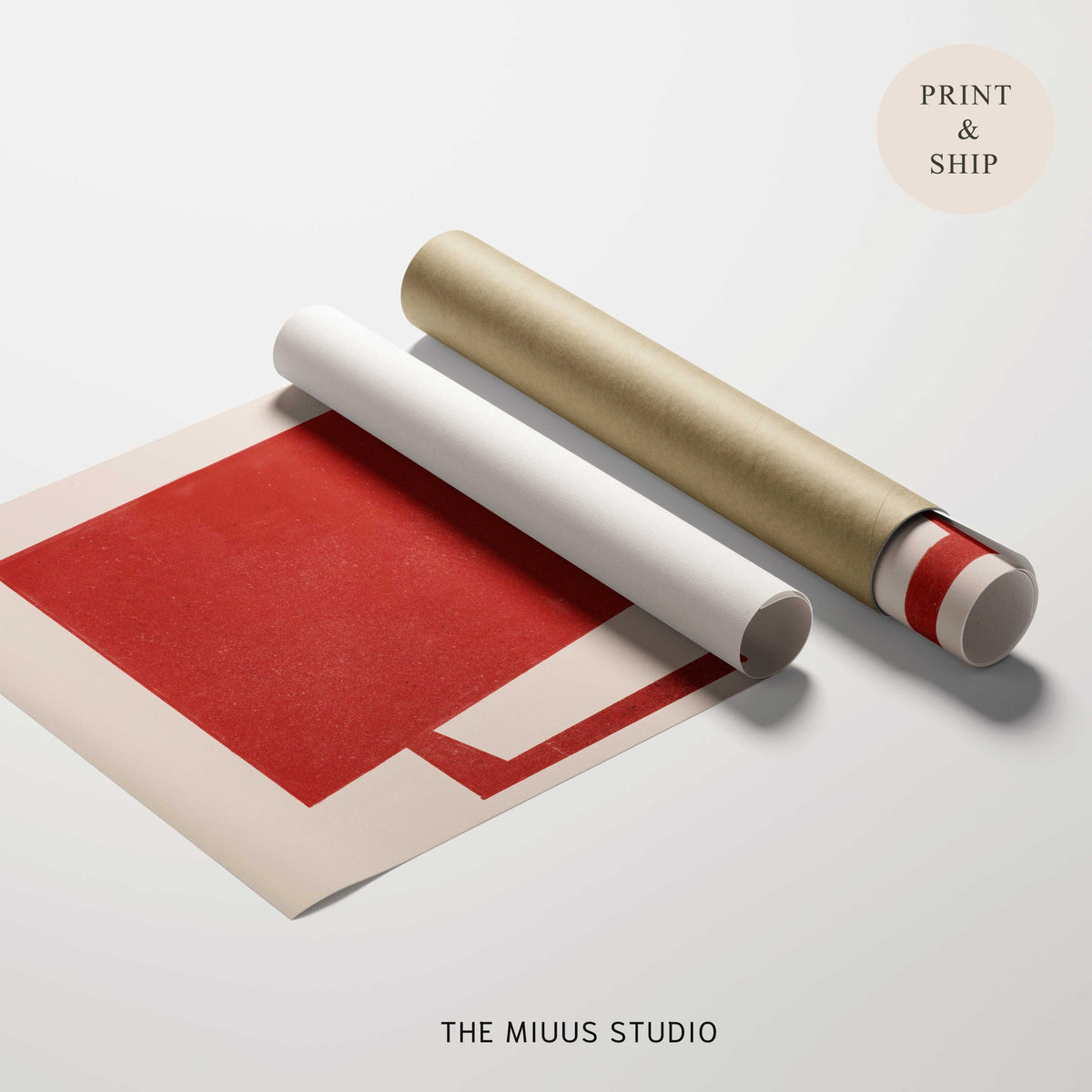 A rolled sheet of red and white paper or wrapping paper displayed on a light gray surface, with a metallic gold tube placed diagonally across it. A beige circle in the top right reads 'PRINT & SHIP' and 'THE MIUUS STUDIO' appears at the bottom.